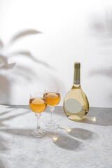 Glasses and bottle of white wine with blank label on light background. Wine making and wine degustation concept. Free space for your text