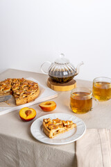 Homemade apple pie on cutting board and glass teapot with cups on a family table. Autumn baking