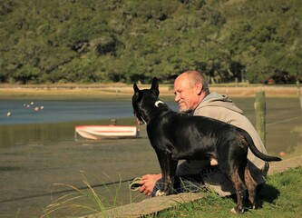 Senior man with his dog at water