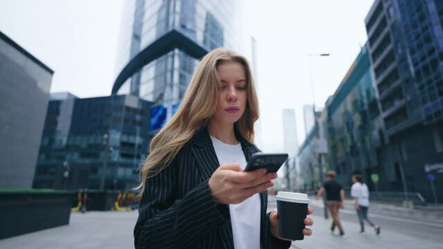 portrait of beautiful businesswoman sending message by smartphone in center of megapolis