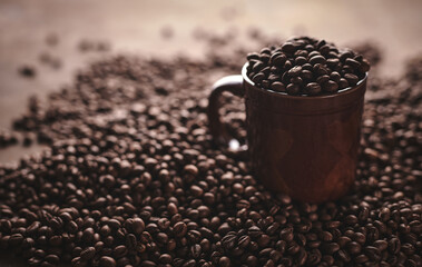 Cup of freshly brewed roasted coffee beans on brown background