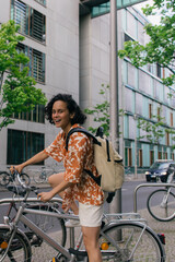 Plakat excited young woman in summer outfit riding bicycle on street in berlin.