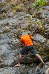 Obraz premium Young indian man hiking with barefoot in vibhooti waterfalls