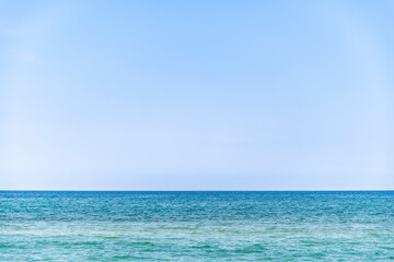 Fototapeta na wymiar calm sea during summer with large copy space in the light blue sky, Ghisonaccia, Corsica, France, horizon over water
