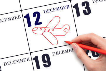 12th day of December. A hand drawing outline of airplane on calendar date 12 December. The date of flight on plane. Travel, business trips. Winter month. Day of the year