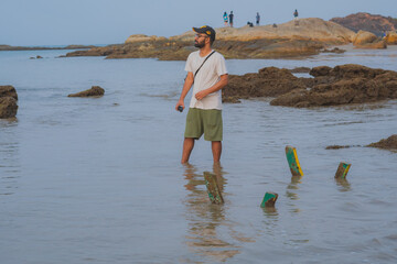Man standing on beach holding gopro