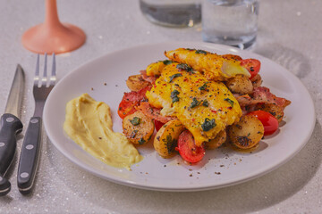 Smoked haddock fillets on a bed of vegetables with herbs and a fish sauce.