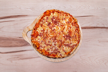 Family pizza with pineapple, ham and lots of cheese on a freshly baked wooden board
