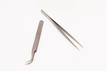 Tweezers and utensils for nail grooming on a white surface