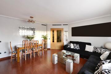 Living room of a residential home with a wooden dining table with matching chairs, a corner sofa...