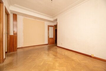 Fototapeta na wymiar Empty living room of a residential house with herringbone oak parquet floors and wooden carpentry on the doors and skirting boards