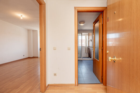 Entrance hall of a house with a cherry wood door, matching wooden floors and white painted walls