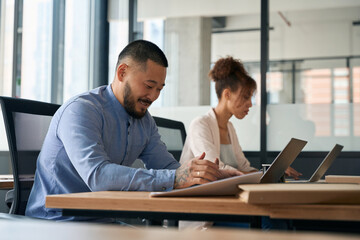 Portrait of colleagues working in bright office, sitting at laptops