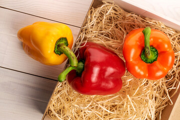Three whole organic fresh juicy tasty bell peppers, close-up, on light wood shavings, lying on a...