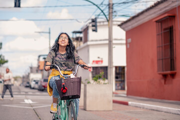 Hispanic girl riding a bicycle.  A girl goes to school by bicycle with her books in the basket. © SALMONNEGRO