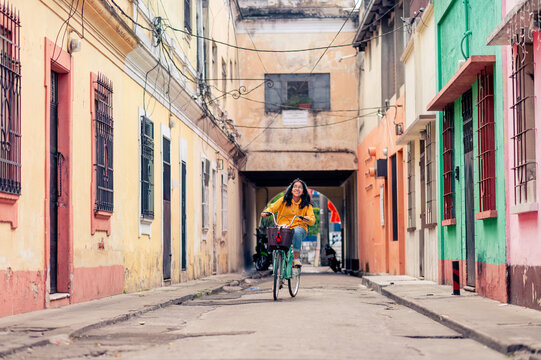 Fototapeta Young woman on a bicycle. Beautiful Hispanic teen riding a bike in Guatemalan neighborhood .