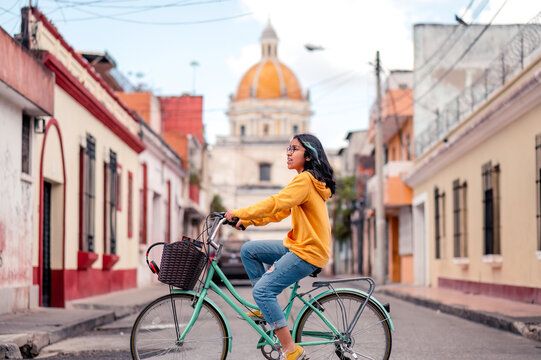 Young woman on a bicycle. Beautiful Hispanic teen riding a bike in Guatemalan neighborhood.