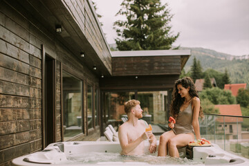 Young couple enjoying in outdoor hot tub on vacation