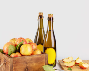 Apple cider drink or fermented fruit drink. Bottles with cider and red organic apples in a wooden box on a kitchen table. Healthy eating and lifestyle concept. Apple, low alcohol drink