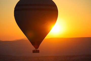 Montgolfière dans le ciel durant le lever de soleil en Cappadoce