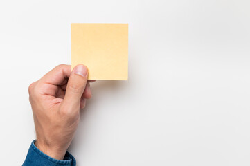 Fototapeta premium A man's hand is holding a yellow sticker. Writing notes, daily plans and reminders. Place for text