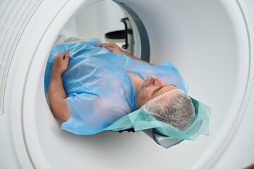 Man lies in tomograph chamber on diagnosis abdomen in medical center