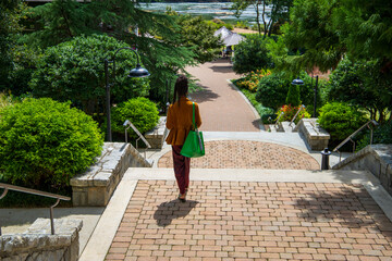 an African American woman wearing a brown jacket and burgundy pants walking down a staircase...
