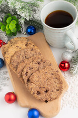 Chocolate chip cookies on a wooden board, a cup of coffee and Christmas decor.