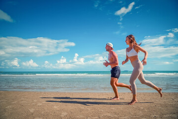 Fototapeta na wymiar Sport man and woman running on beach at sunset