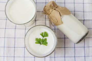 Two glasses of ayran on a light background linen towel, next to it lies a bottle of ayran
