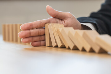 Protection finance from domino effect concept. Hands stop domino effect before destroy stack of money..
