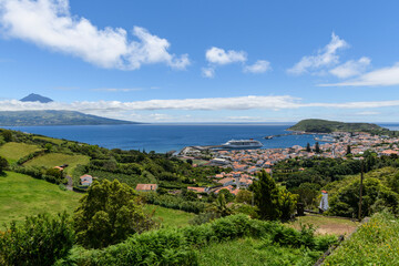 Fototapeta na wymiar View over Horta to the Pico volcano / View over the town of Horta on the island of Faial, a cruise ship is moored in the harbor, on the horizon you can see the Pico volcano, Azores, Portugal.