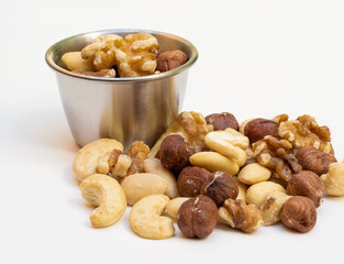 close up of stainless steel bowl and nuts isolated on a white background