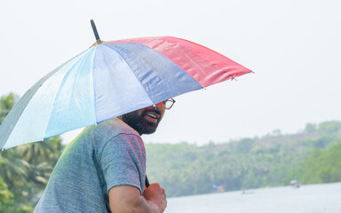 Man holding rainbow umbrella looking back
