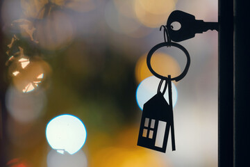 The key with keyring in the door keyhole with blurred night lights background, selective focus