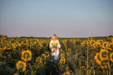 Fototapeta premium Summer evening. Girl in a field with sunflowers.