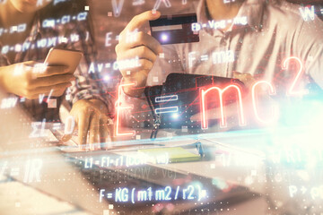 Double exposure of man and woman on-line shopping holding a credit card and formulas hologram drawing. Education E-commerce concept.