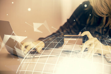 Double exposure of woman on-line shopping holding a credit card and world map hologram drawing. International E-commerce concept.