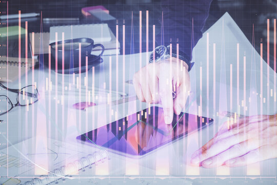 Double exposure of man's hands holding and using a digital device and forex graph drawing. Financial market concept. © peshkova