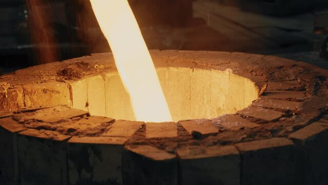 A Stream Of Molten Metal Flows Into A Melting Furnace. Steam And Sparks Fly Out Of The Furnace. Metalworking. Metallurgy. Close-up. 4K