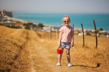 Preschooler girl going to beach at Atlantic coast of Normandy, France. Outdoor summer activities for kids