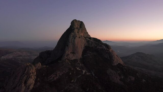 Aerial view of Pena de Bernal mountain with rocky hills in Mexico at sunset