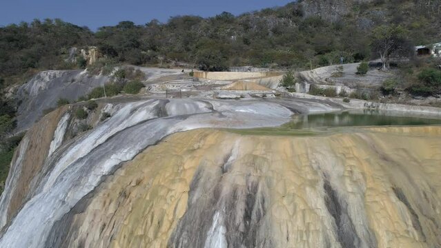 Raising drone shot of Hierve el Agua waterfall with forest mountains around in Mexico