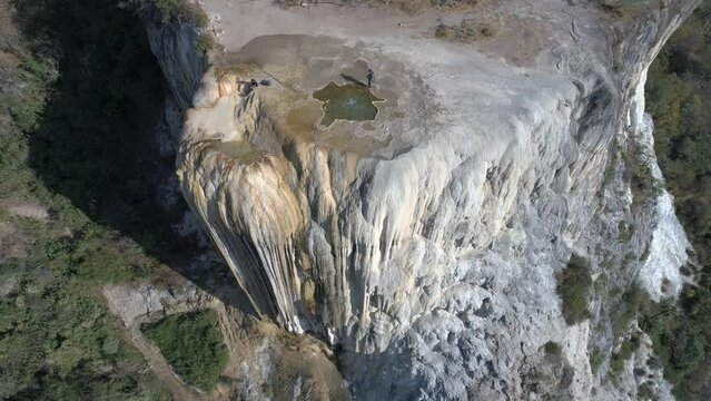 Drone shot of Hierve el Agua rocky cliff with forest mountains in Mexico