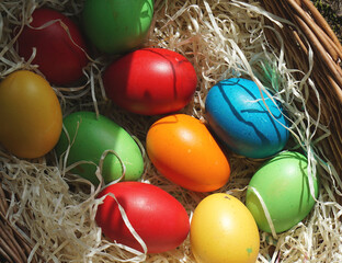 self-dyed Easter eggs in artificial decorative straw and woven basket