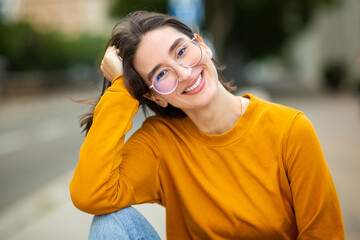 Portrait of beautiful young woman with eyeglasses sitting outside