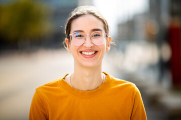 Portrait of cheerful young woman with eyeglasses standing outside