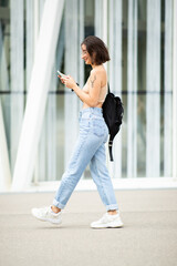 Stylish woman walking with bag and mobile phone in the city