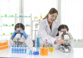 happy kids studying science in laboratory, female scientist as a mentor is teaching the students