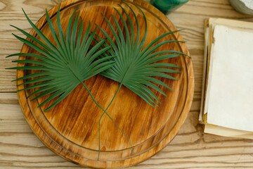 green palm leaves lie on cutting board on wooden table